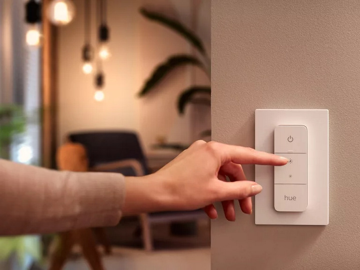 Ruka ovládající jas osvětlení pomocí nástěnného stmívače Philips Hue Dimmer Switch.