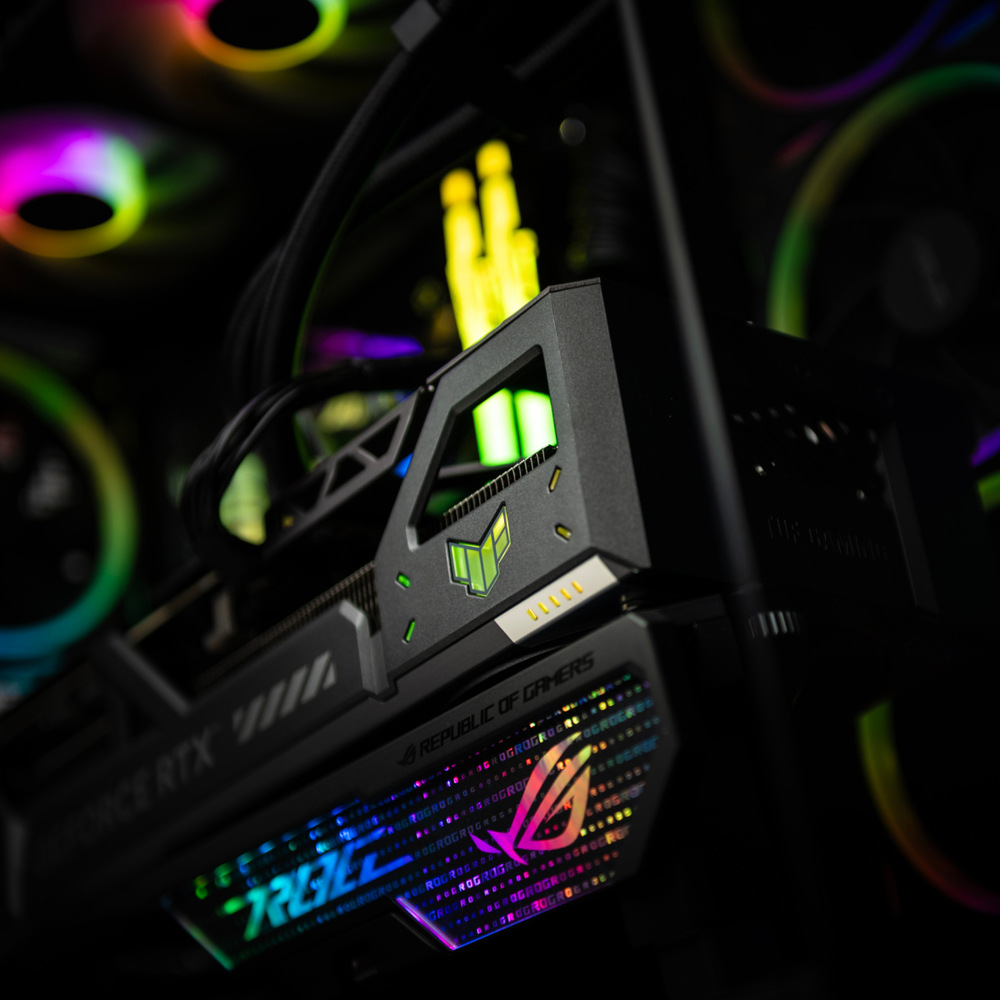  Detailní záběr na špičkovou herní grafickou kartu s živým RGB osvětlením. Grafická karta se vyznačuje propracovaným designem a futuristickou estetikou, která vyjadřuje výkon a sofistikovanost.