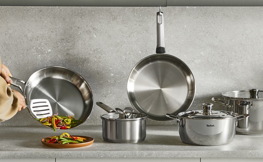 Pánev WOK Tefal Extreme E5291904, 28 cm nerez Sada kuchyňského náčiní spolu s WOK pánví je rozložená na kuchyňské lince.