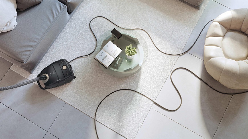 HE410P 011 vysavač je uprostřed místnosti a za ním dlouhý kabel