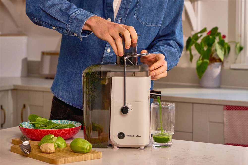 Odšťavňovač RUSSELL HOBBS Juice Luxe Stone 28770-56 béžový Muž vkládá ovoce do odšťavňovače Russell Hobbs
