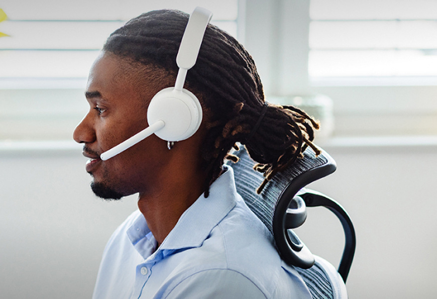 Boční profil muže sedícího na kancelářské židli s nasazeným headsetem Logitech Zone Wireless 2 ES a vyklopeným mikrofonem