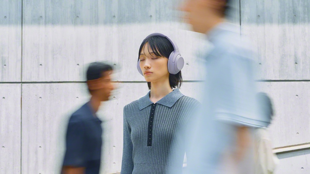 Žena při chůzi městem má na sobě sluchátka Sony WH-1000XM4C 