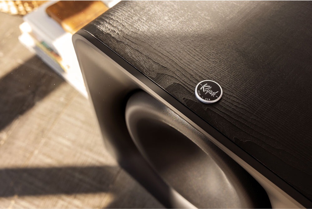 Subwoofer Klipsch Flexus SUB 200 černý Subwoofer Klipsch Flexus SUB 200 při pohledu zblízka a shora, vedle subwooferu jsou položeny knihy