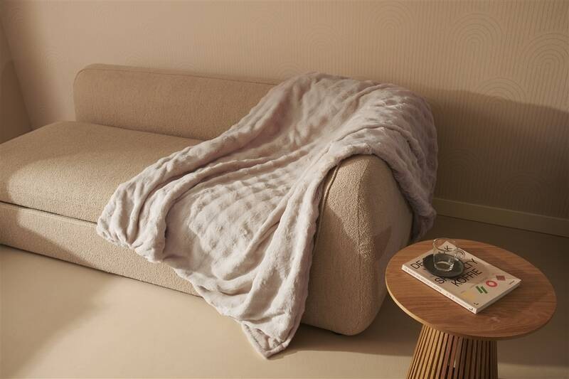 Vyhřívací deka Duux DXOB12 Yentl Cuddle 200 x 200 cm šedá Nadrozměrná šedá deka Duux Yentl volně přehozená přes textilní pohovku vedle dřevěného stolku s časopisem v jemně laděném moderním obývacím prostoru.