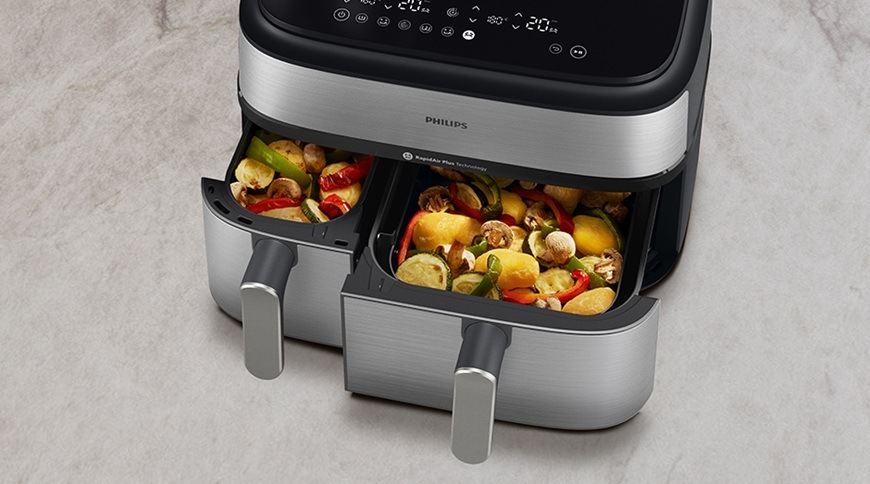 Fritéza horkovzdušná Philips Airfryer Dual Basket 5000 series 9 l, NA555/00 stříbrná Horkovzdušná fritéza Philips NA555/00 má povysunuté oba košíky. Uvnitř nich se právě připravila lahodná zelenina.