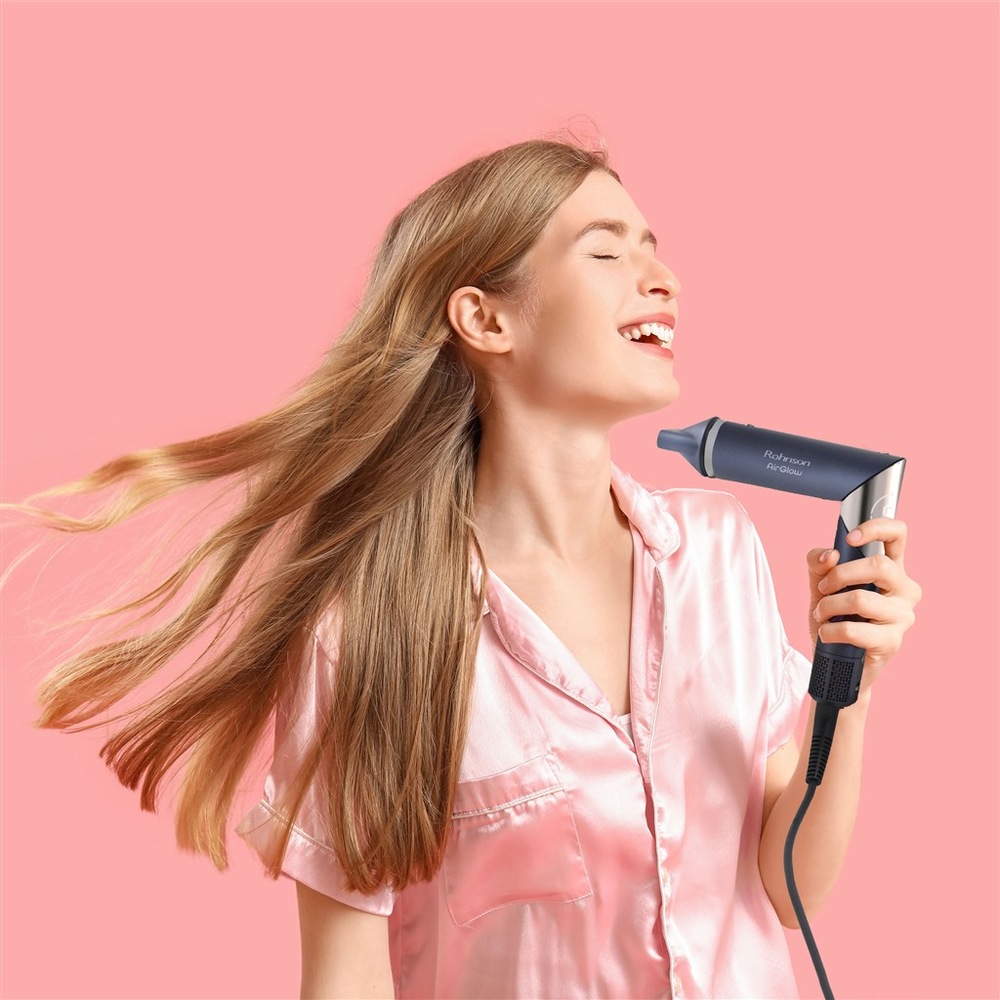 Styler Rohnson R-688 AirGlow tmavě modrý Žena drží v ruce styler Rohnson s pozadím růžové