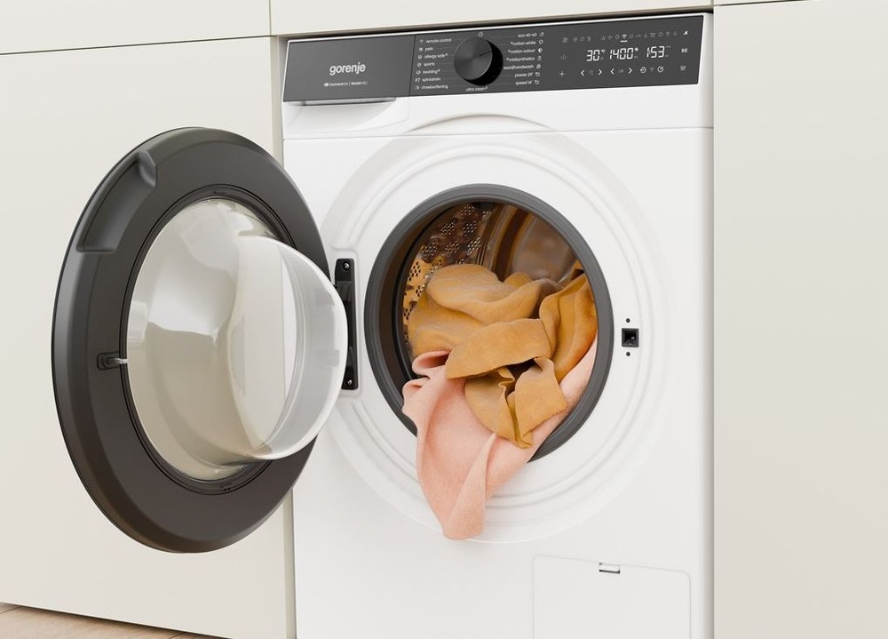 Pračka Gorenje G600 WG614A4P1 FastWashPro bílá bílá pračka gorenje fastwashpro zabudovana ve skřínove stěně. Visi z ní oranžové prádlo.