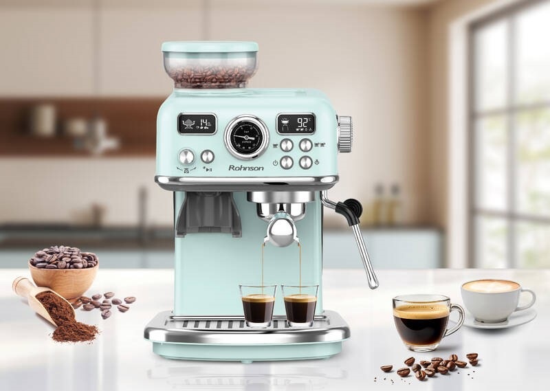 Elegantní pákový kávovar Rohnson R-98250G 2v1, který právě připravuje současně dvě kávy, vedle něho je postaven šálek s cappuccinem a jako dekorace je obrázek doplněn kávovými zrny i namletou kávou.