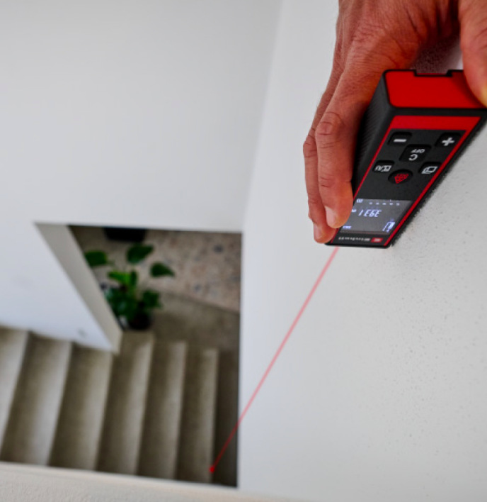 Laserový dálkoměr Einhell Classic TC-LD 60 R při měření vzdálenosti podél schodiště v interiéru