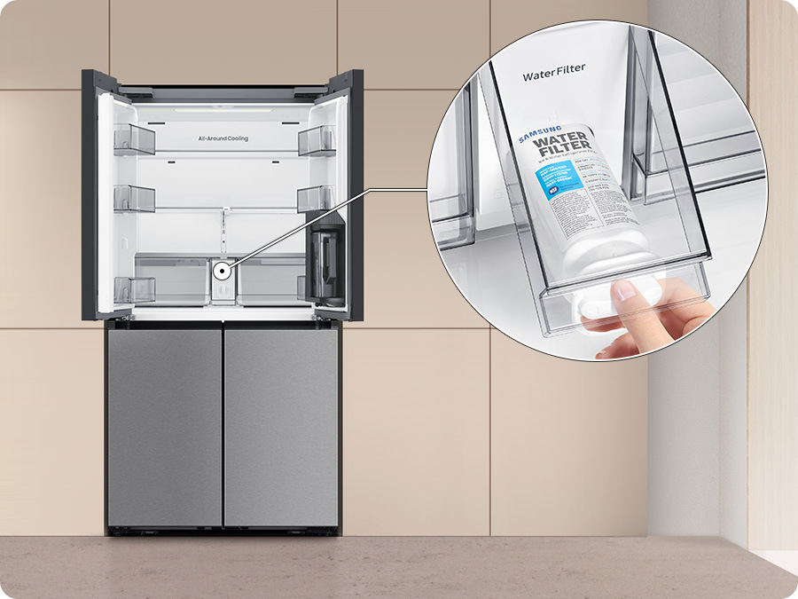 Americká lednice Samsung RM70F63NEREO nerez/ocel Americká lednice Samsung RM70F63NEREO stojí v kuchyni, dveře chladicí části jsou otevřené dokořán, vpravo je v kroužku detail vodního filtru v zásuvce