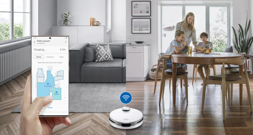 Robotický vysavač Samsung Jet Bot Koláž dvou obrázků, vlevo je obývací pokoj, vpravo rodina u jídelního stolu, uprostřed je vysavač Samsung Jet Bot se symbolem Wi-Fi, vlevo je ruka držící mobilní telefon s aplikací SmartThings