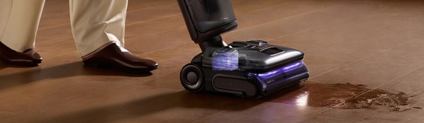 Muž za pomocí tyčového vysavače Roborock F25 Ultra uklízí mastnou nečistotu na podlaze.