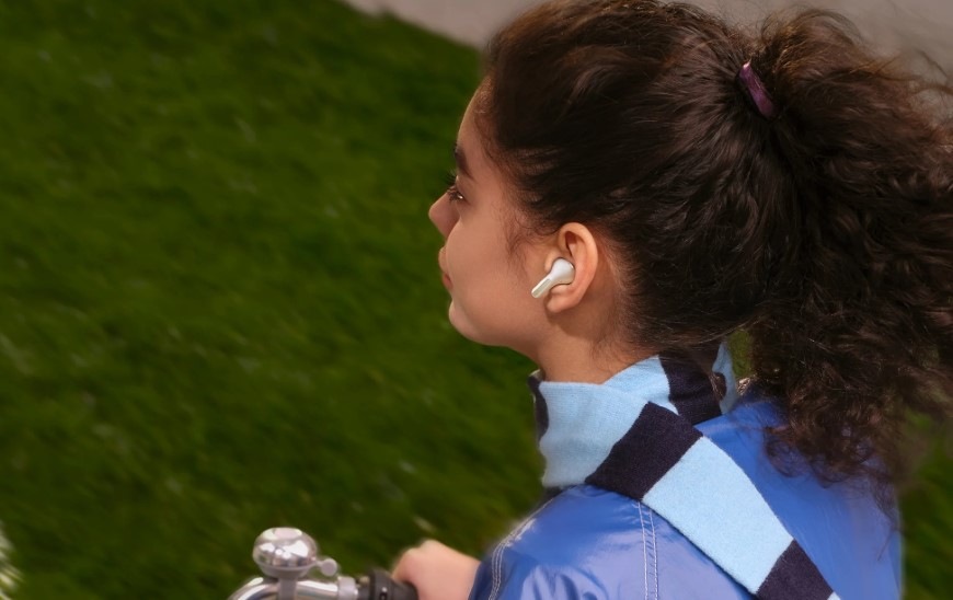 Sluchátka Xiaomi REDMI Buds 8 bílá Žena jedoucí na kole má v uších sluchátka Xiaomi REDMI Buds 8 s potlačením šumu v mikrofonech