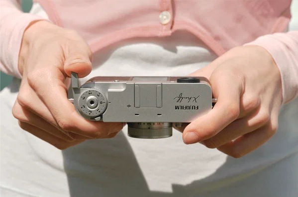 Digitální fotoaparát Fujifilm X half černý Horní pohled na fotoaparát Fujifilm X half držený oběma rukama s dobře dostupným voličem expozičních režimů