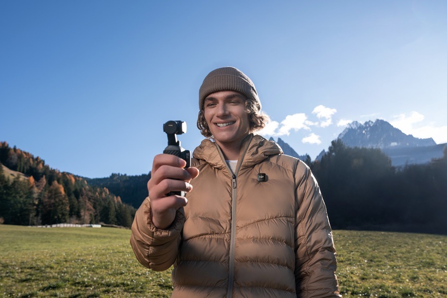 Outdoorová kamera DJI Osmo Pocket 4 Standard Combo černá Muž stojící na louce drží kameru.