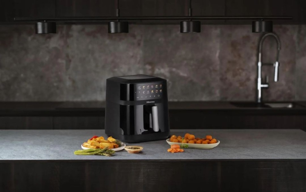 Fritéza horkovzdušná Hisense HAF1800DCD DUAL HEATER černá zapnutá horkovzdušna fritéza Hisense HAF1800DCD DUAL HEATER na kuchynské lince. Vedle na talířích jsou potraviny.