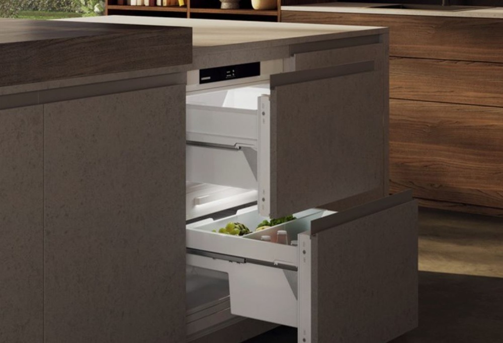 Detail na lednici lednici Liebherr s vysouvacimi zasuvkami, která je zabudovana do tmave kuchynské linky.