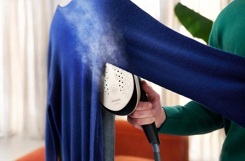 Žena napařuje halenku na ramínku žehličkou Philips AIS8540/80 Series 8500
