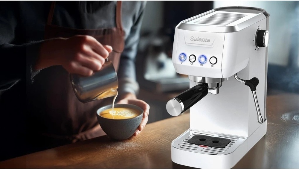 Barista připravující latte art vedle kávovaru Salente COFFIO 2026 na barové desce.