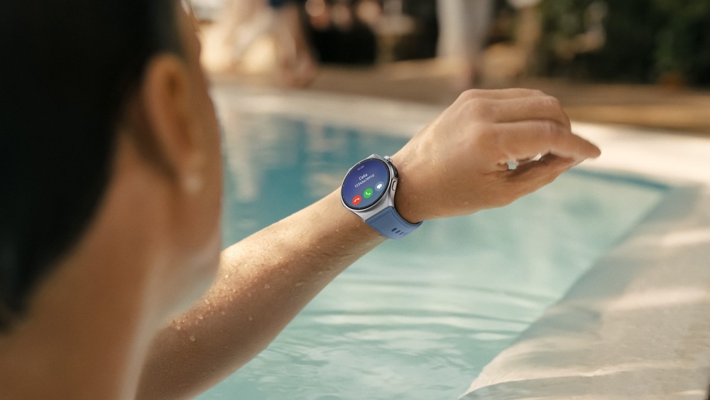 Chytré hodinky Huawei Watch 6 42 mm zlaté Muž v bazénu sleduje displej chytrých hodinek; na obrazovce je zobrazen příchozí hovor s tlačítky pro přijetí a odmítnutí