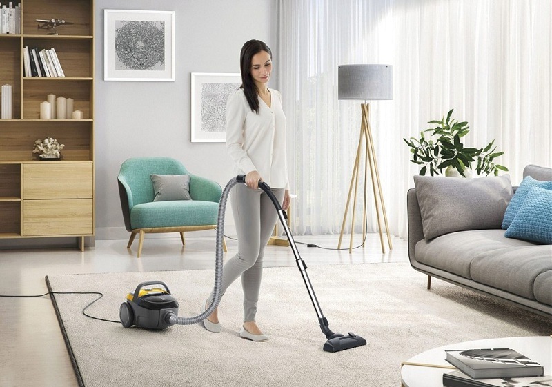 Podlahový vysavač Electrolux CompactGo Cyclonic ECGC21-2Y žlutý Žena v obývacím pokoji vysává koberec s pomocí vysavače Electrolux.