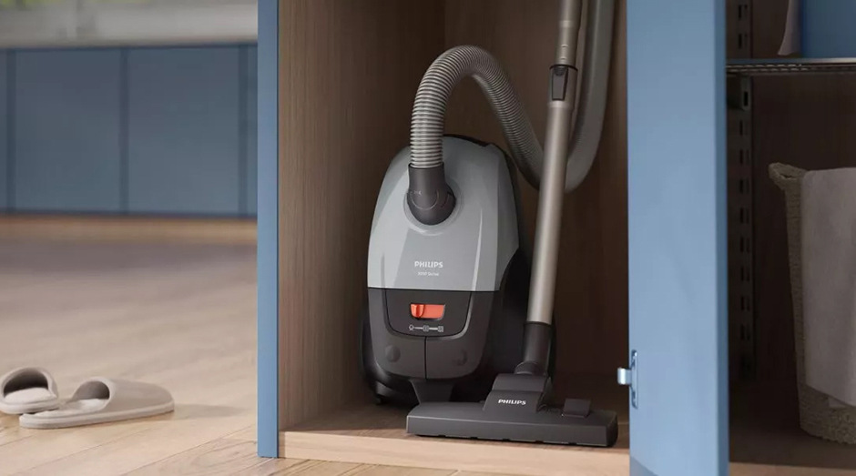 Kompaktní sáčkový vysavač Philips XD2152/12 2000 Series uložený ve skříni pro snadné skladování.