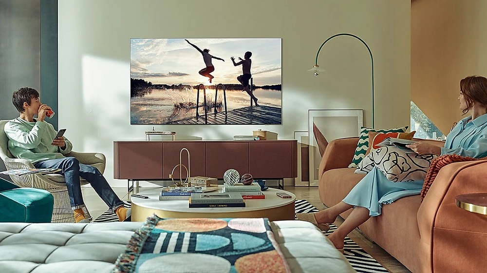 Televize Samsung QE98QN90A Muž a žena sedí v obývacím pokoji a sledují z boku televizi