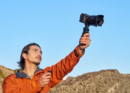 Muž v horách drží ve výšce fotoaparát na gripu Sony GP-VPT3