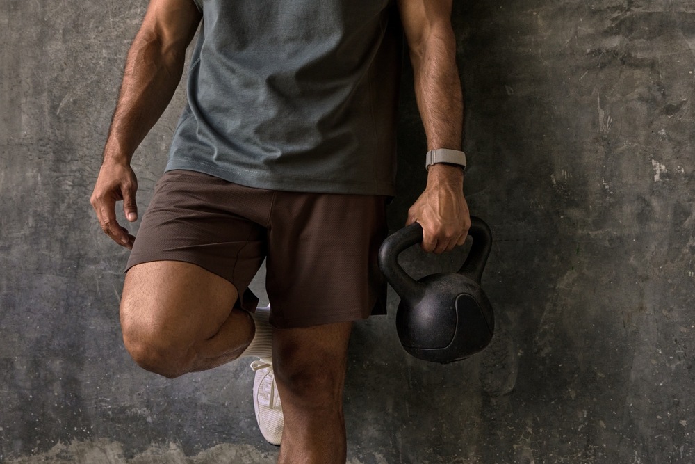 Fitness náramek Garmin CIRQA™ Smart Band S/M růžový Detail muže svírajícího kettlebell v ruce s fitness náramkem Garmin CIRQA Smart Band
