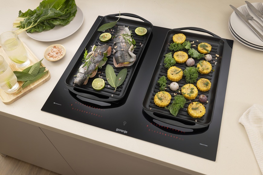 Indukční varná deska Gorenje G800 GI6443BSCWF černá Na varné desce Gorenje jsou položeny dva dlouhé pekáče. V levém pekáči je ryba, v pravém zas zelenina.