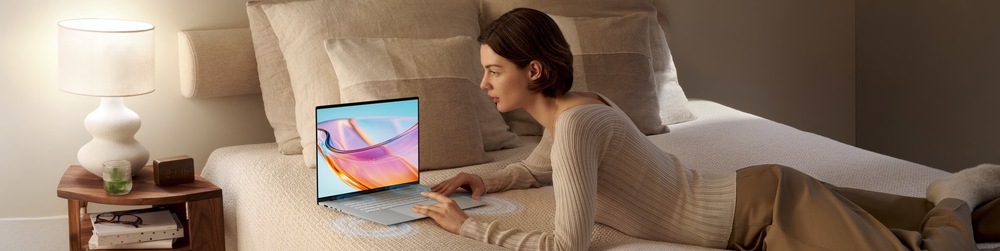 Notebook Asus Zenbook S16 šedý Žena sleduje film na displeji notebooku Asus Zenbook S16 z pohodlí postele
