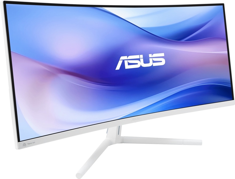 Na obrázku je monitor Asus VU34WCIP-W 34" v bílém provedení z předního šikmého pohledu. Má širokoúhlou prohnutou obrazovku, tenké černé rámečky a světlou spodní lištu s logem Asus uprostřed. Monitor stojí na bílém tříramenném stojanu s dlouhými štíhlými nohami. Celkově působí elegantně a moderně, vhodně pro pracovní stůl i domácí kancelář.