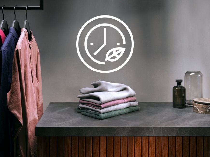 Symbol TimeSave nad poskládanou hromádkou prádla na stole. Vlevo košile na ramínku.
