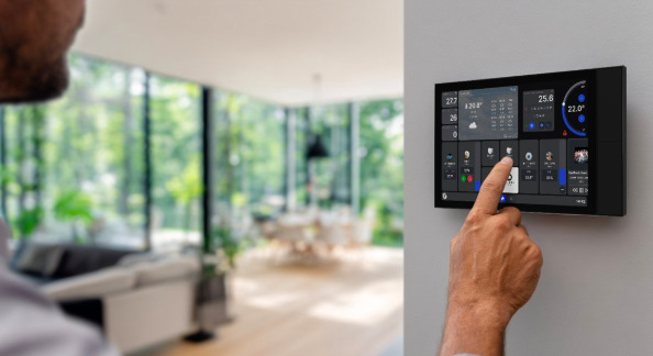 Uživatel ovládá chytrý panel Shelly Wall Display XL na zdi moderního obývacího pokoje