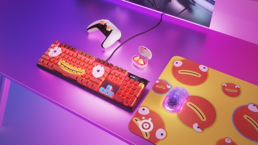 Myš Aerox Fortnite na podložce s motivem Fishstick vedle klávesnice a dalších herních doplňků