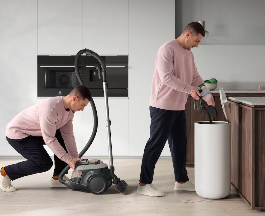 Muž vyndává prachovou nádobu z vysavače Electrolux a v dalším kroku vysypává její obsah do koše. V pozadí je kuchyně s vestavnými spotřebiči Electrolux.