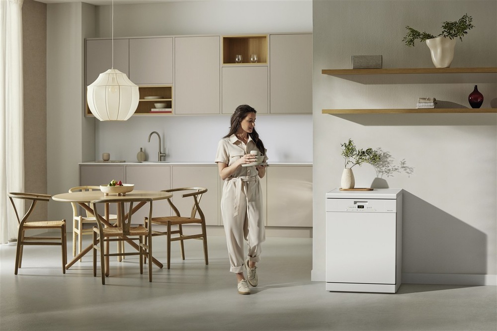 Myčka nádobí Miele G 5611 SC Active bílá V kuchyni stojí žena držící šálek a dívá se na myčku Miele G 5611 Active