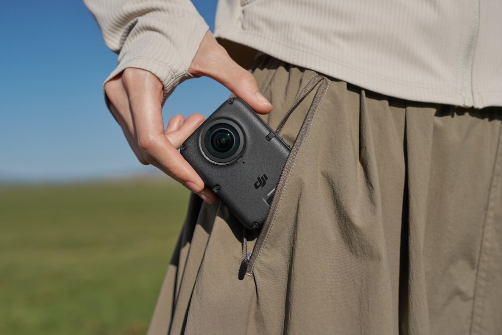 Outdoorová kamera DJI Osmo 360 II Adventure Combo černá Žena si dává kompaktní outdoorovou kameru do kapsy
