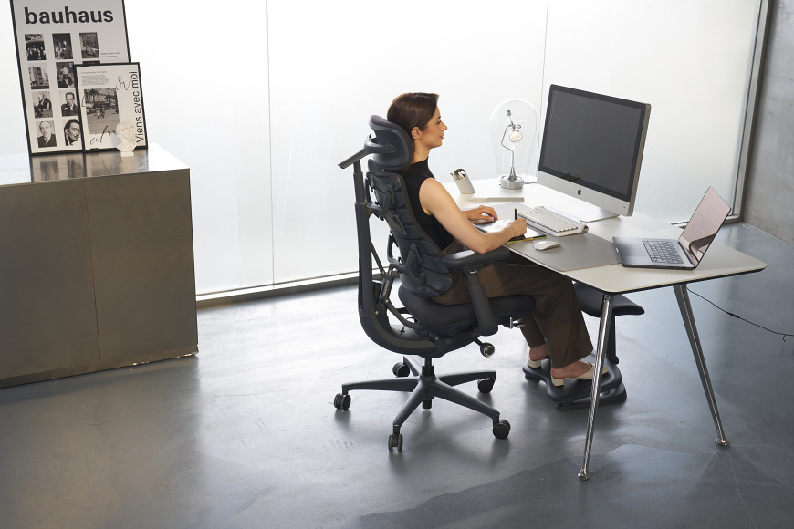 Žena sedící na ergonomické židli u pracovního stolu