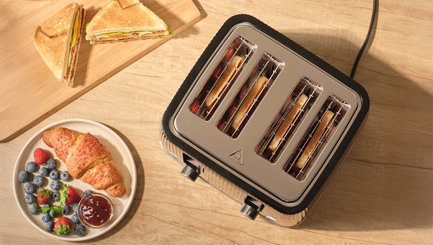Topinkovač Sencor STS 7541BK černý Pohled shora na topinkovač Sencor se čtyřmi opékanými toasty na kuchyňské lince vedle croissantu, ovoce a sendviče.