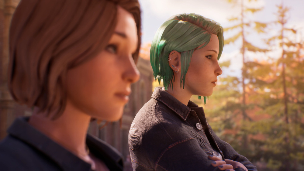 Hlavní postavy hry Life is Strange: Reunion v klidném podzimním prostředí. Jedna má krátké hnědé vlasy, druhá zelené, obě jsou oblečené v tmavých bundách. Vypadají zamyšleně.