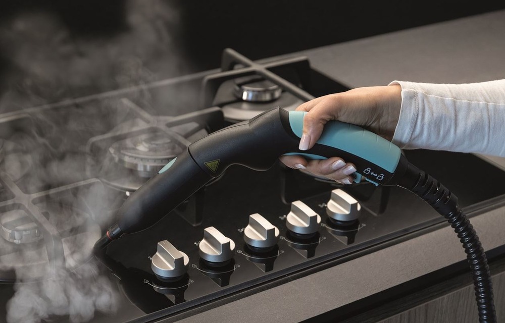Parní čistič Ariete XVapor ART 4145/BL tmavě modrý čištění plynové varné desky parním čističem Ariete ART 4145/BL XVapor. Deska je posazená na šedé kuchyňské pracovní ploše.