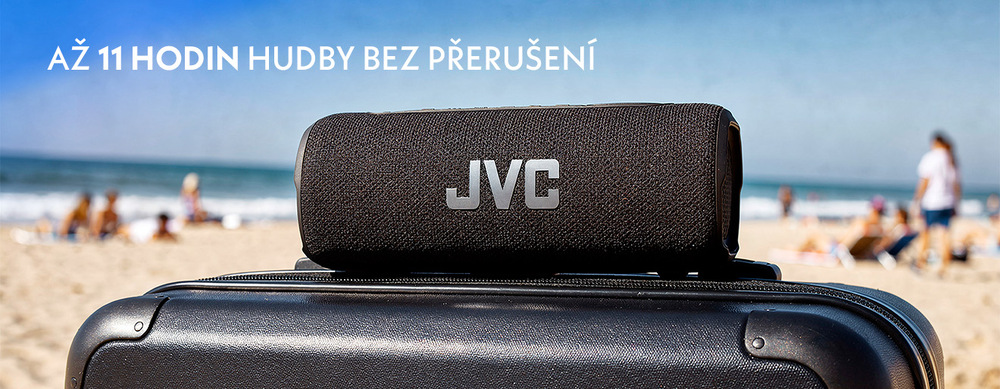 Černý přenosný Bluetooth reproduktor JVC XS-E325B  položený na cestovním kufru na pláži. V horní části je nápis „Až 11 hodin hudby bez přerušení“.