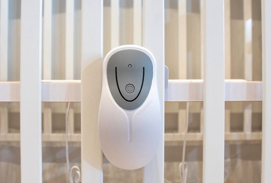 Řídicí jednotka monitoru dechu Babysense 8 připevněná na bočnici postýlky