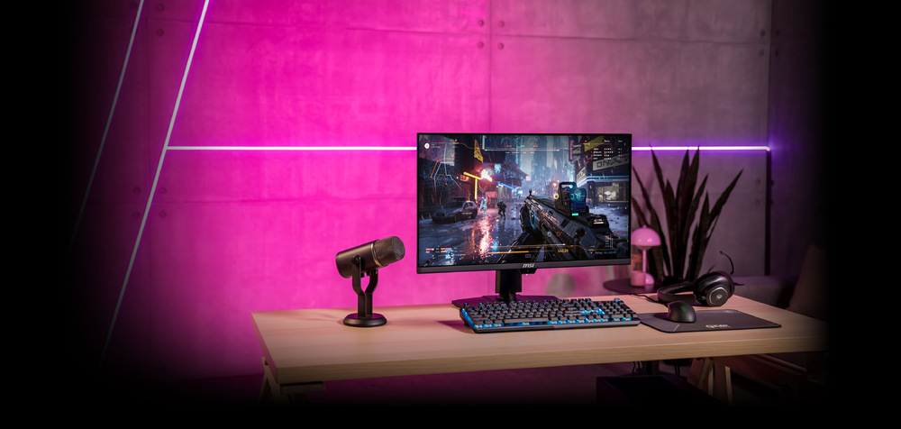  Stylová herní sestava s monitorem zobrazujícím futuristickou městskou scenérii. Na stole mikrofon, klávesnice a sluchátka. Růžová neonová světla vytvářejí živou atmosféru.