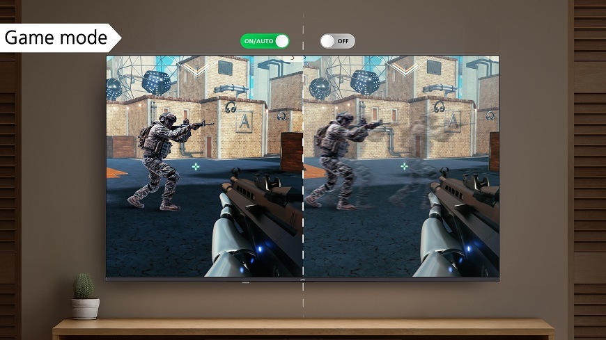 Televize JVC LT-65VDQ9435 Herní režim televize JVC visící na stěně obývacího pokoje, zlepšující plynulost a ostrost obrazu při hraní, znázorněný rozdílem rozdělené obrazovky při hraní FPS hry