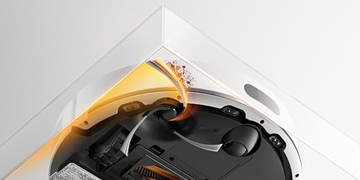 Pohled na Dreame F20 Plus, který v rohu místnosti prodlouženými štětinami vymetává prach.