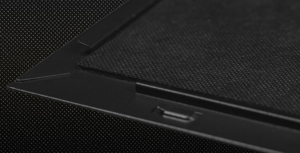 Case Cooler Master Silencio S600 Tempered Glass černá Přiblížený záběr na černou, strukturovanou kovovou mřížku s přesnými geometrickými hranami, připomínající část reproduktoru nebo audio zařízení. Tón je elegantní a moderní.