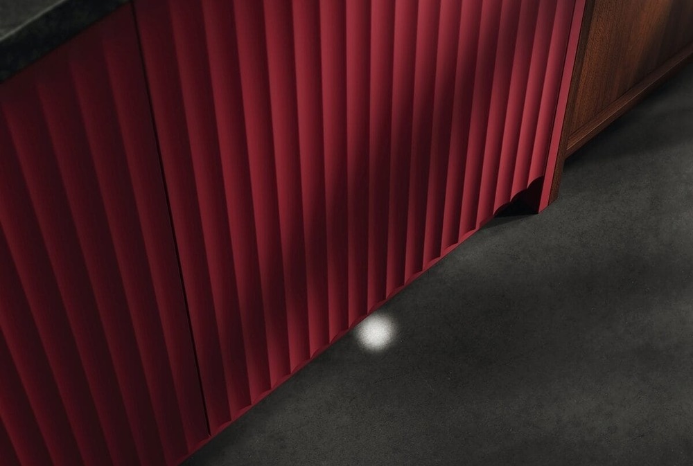Zavřená myčka AEG s červenými dvířky promítá indikátor stavu mytí na podlahu – paprsek LightOnFloor.